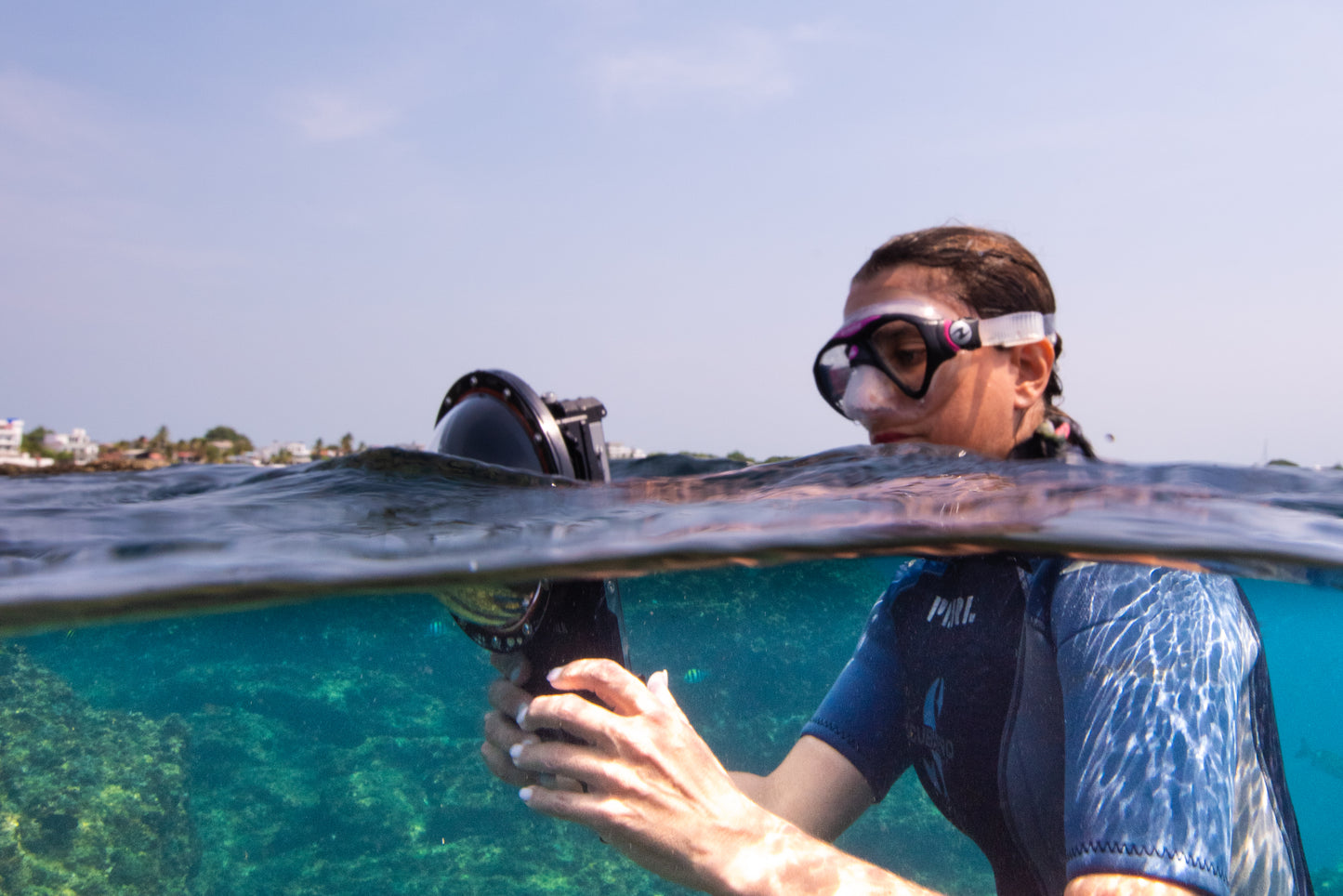 A young lady takes a split shot photo at the surface using the Divevolk Seatouch4 Max Housing and Divevolk Dome Lens