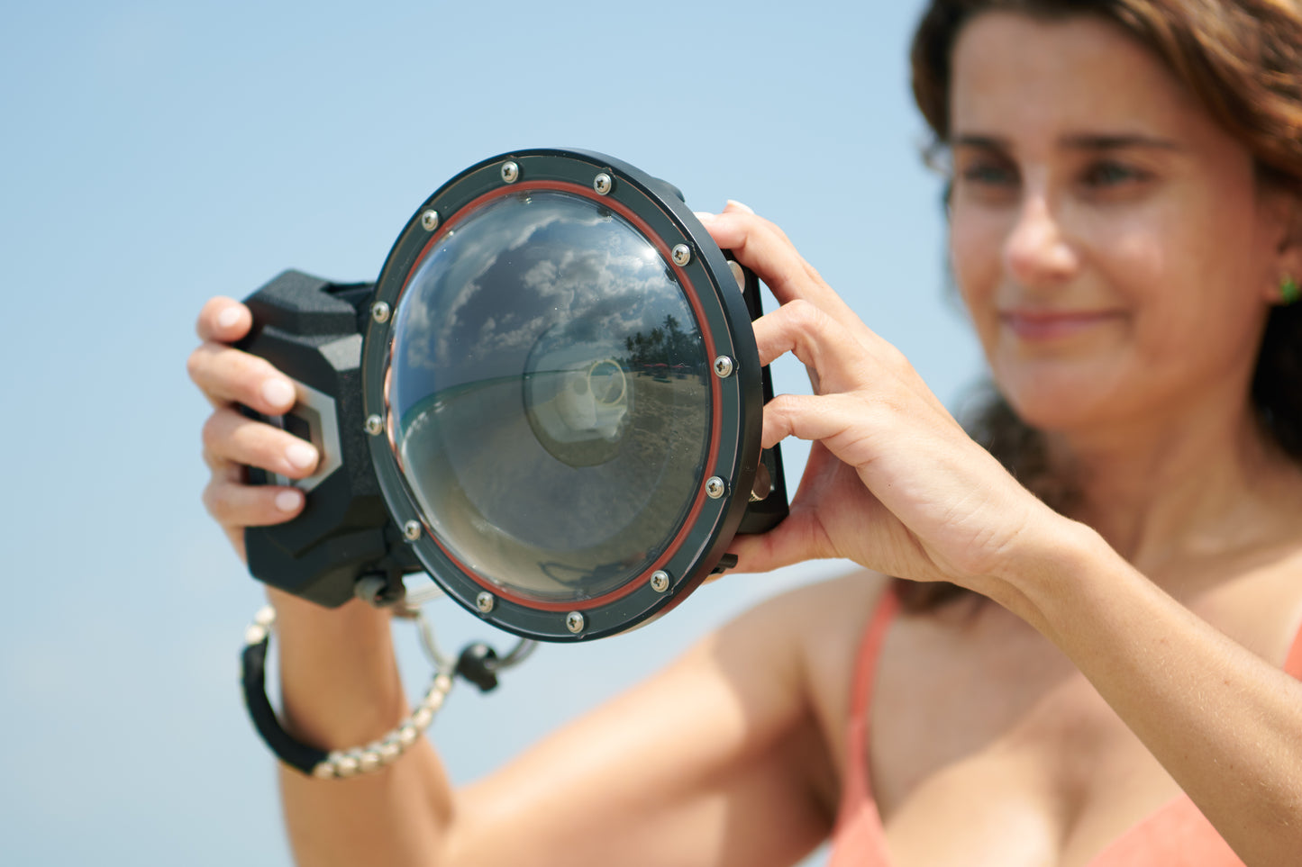 A young lady holds the Divevolk Seatouch4 Max Smartphone housing with the Divevolk Dome Lens installed