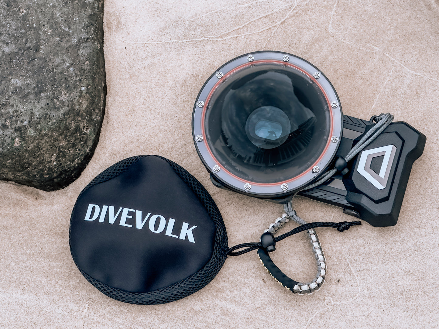The Divevolk Seatouch 4 Max Smartphone Housing face up in the sand with the Dome lens installed