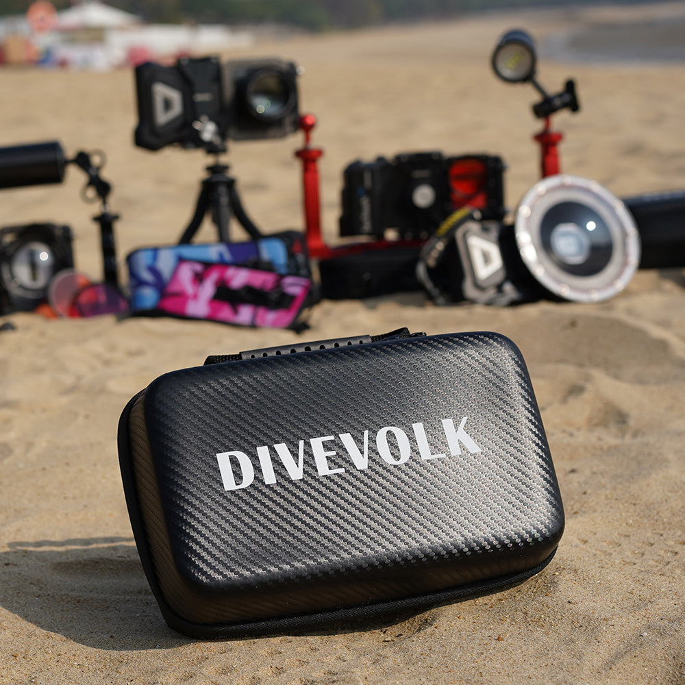 Black 'DIVEVOLK' case on sand with camera equipment in the background