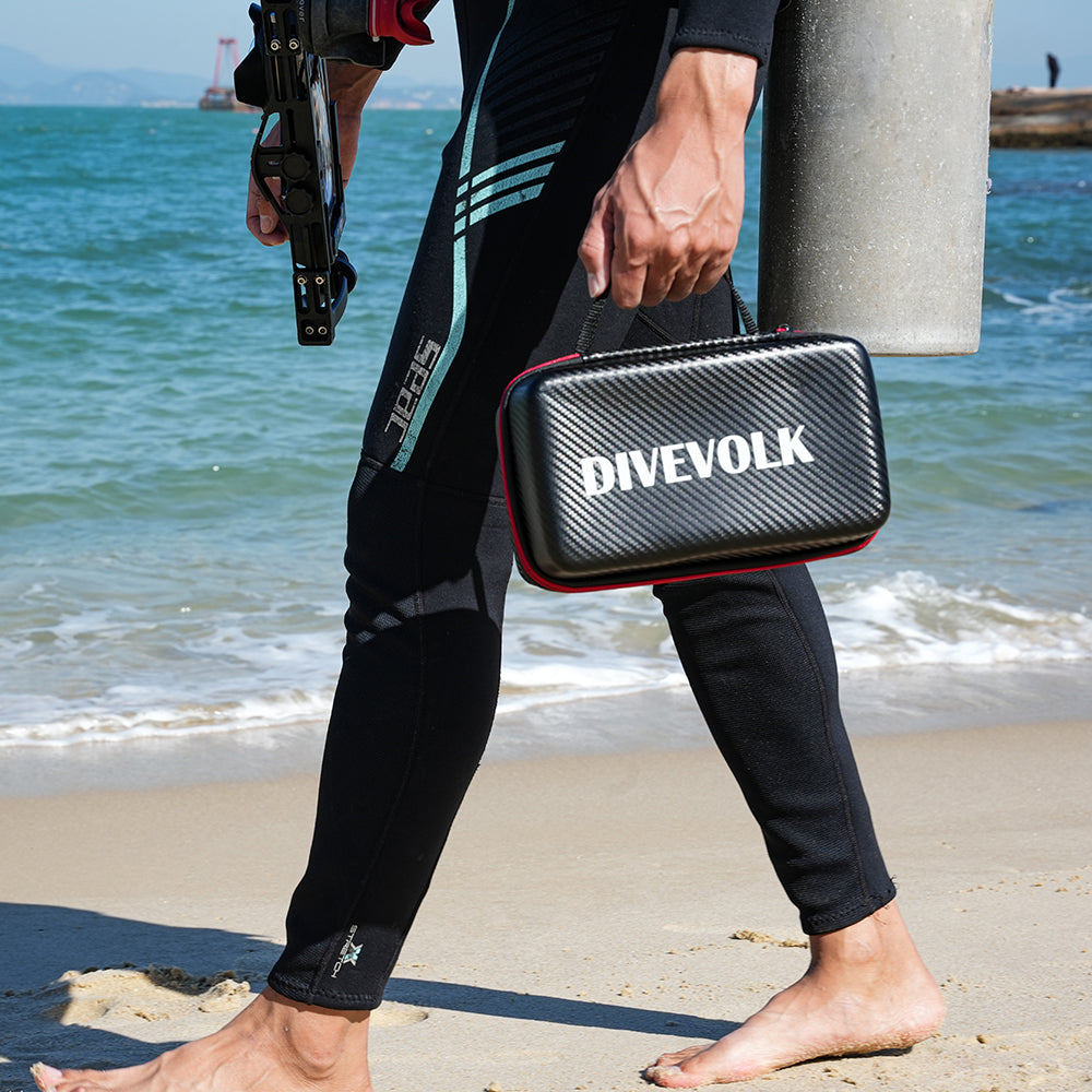 Scuba Diver holding a Divevolk case on a beach with ocean in the background