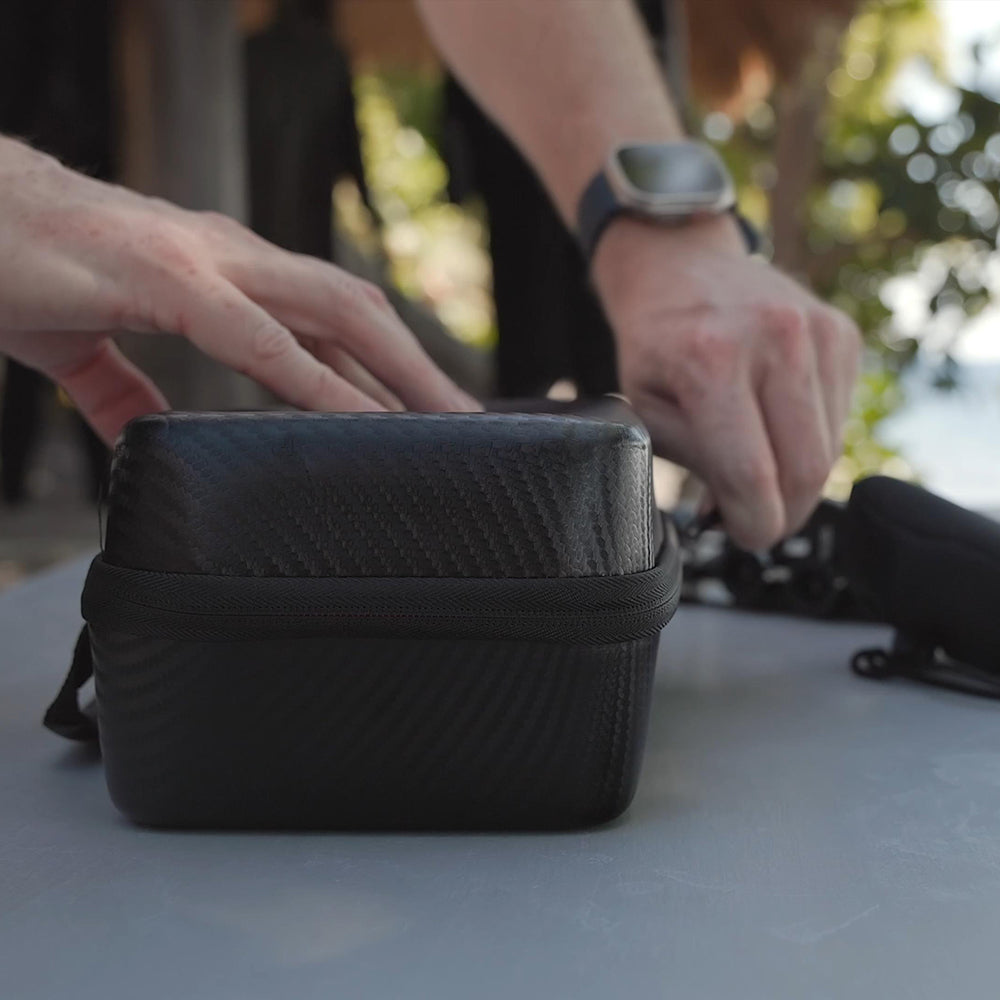 Person interacting with a black textured bag on a light surface