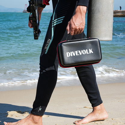 Scuba Diver holding a Divevolk case on a beach with ocean in the background