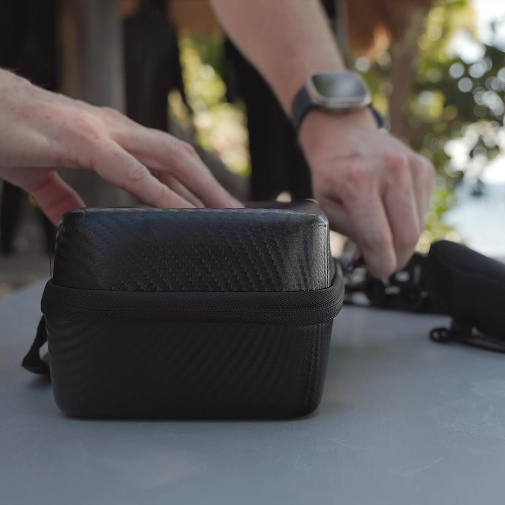 Person interacting with a black textured bag on a light surface