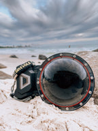 The Divevolk Seatouch 4 Max Smartphone Housing situated on the beach with the Dome lens installed