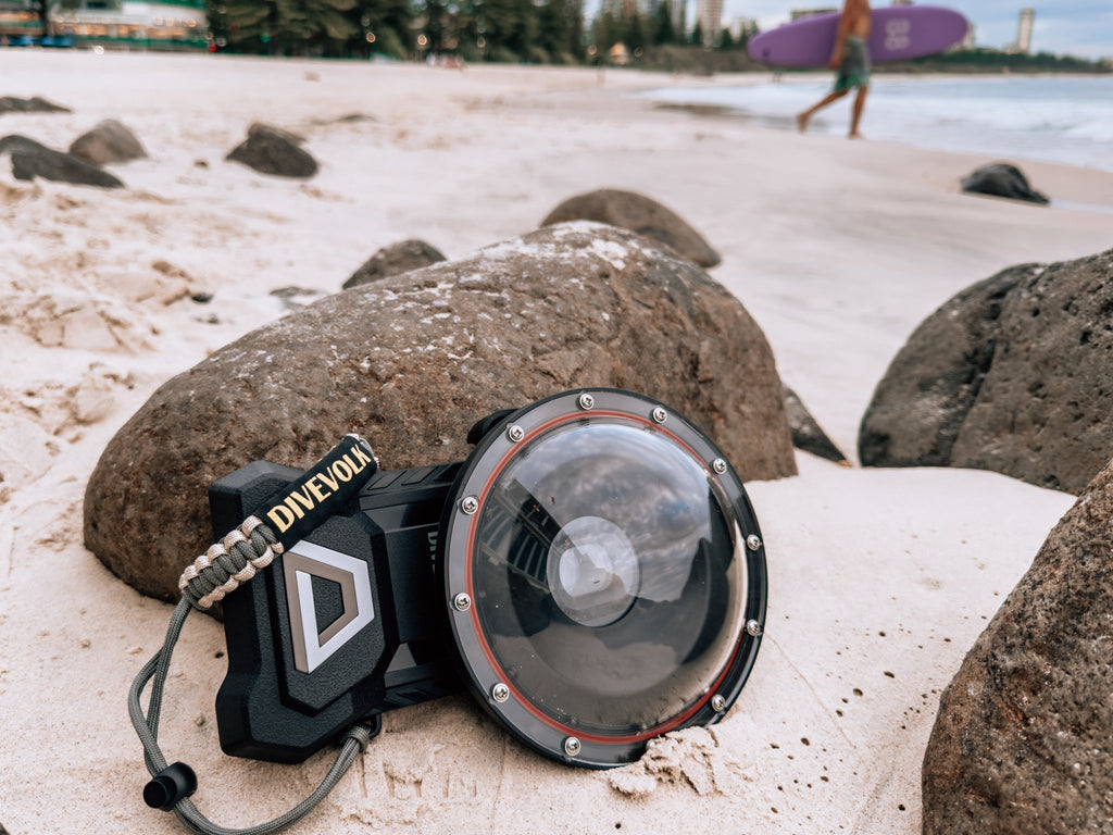The Divevolk Seatouch 4 Max Smartphone Housing situated on the beach with the Dome lens installed