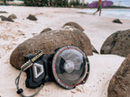 The Divevolk Seatouch 4 Max Smartphone Housing situated on the beach with the Dome lens installed